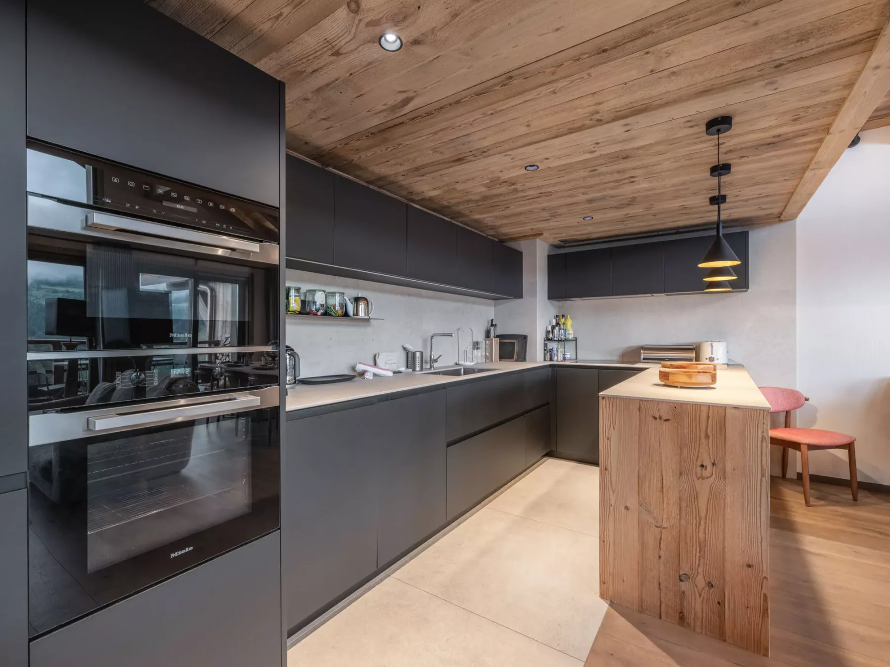 A modern kitchen with dark cabinets, built-in appliances, and a wooden island.