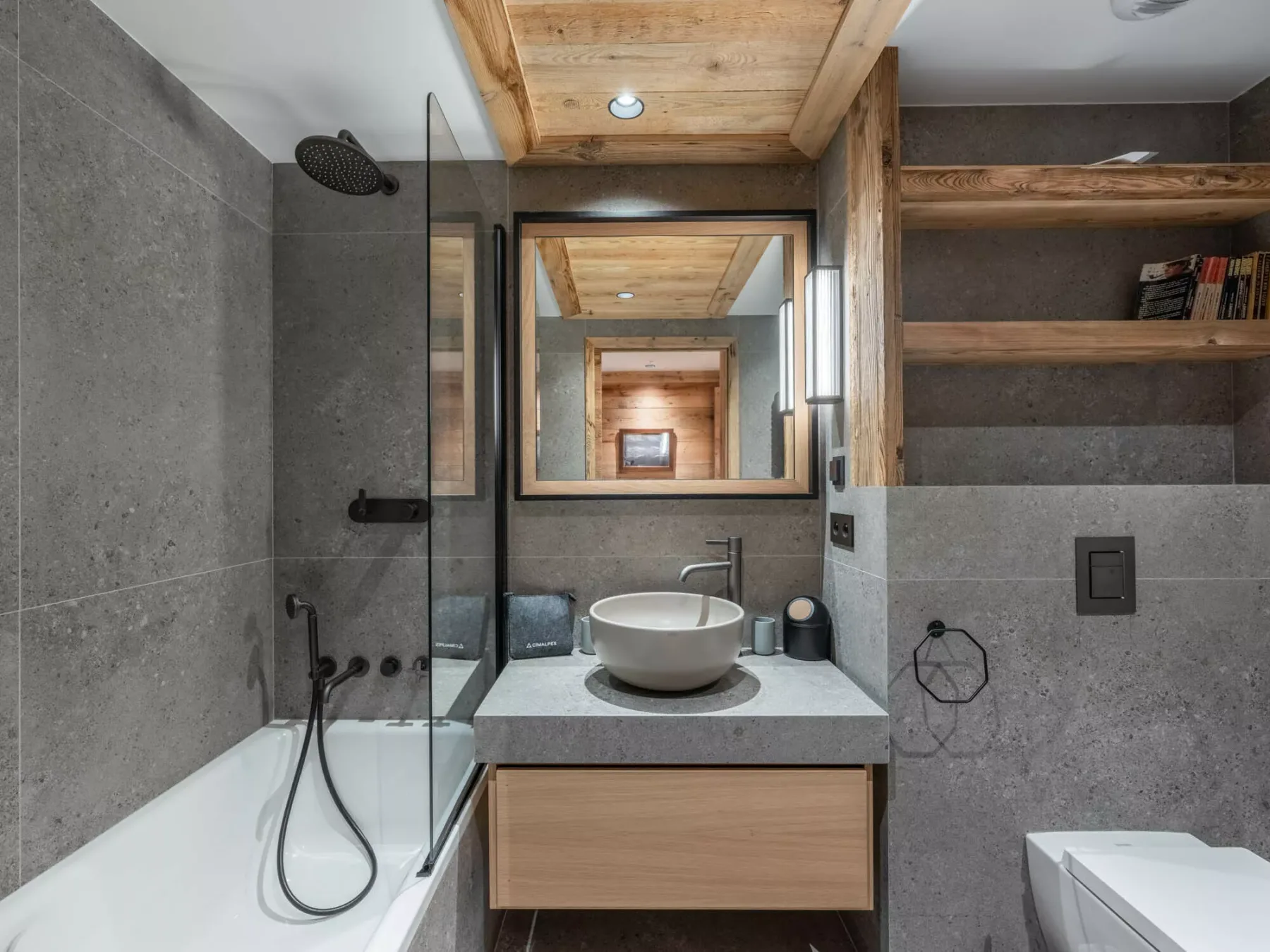A modern bathroom with a bathtub, glass shower screen, and sink vanity.