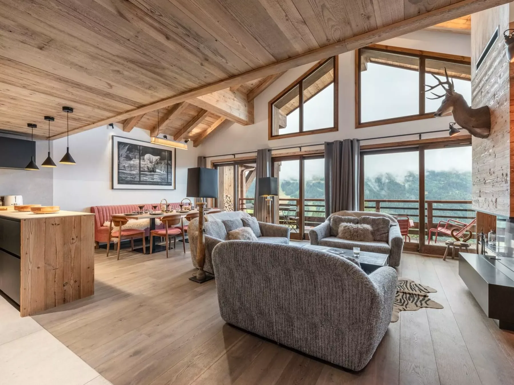 A spacious living and dining area with exposed wooden beams and large windows.