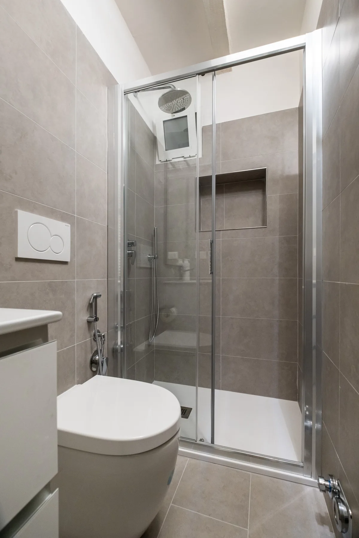 A tiled bathroom with a glass shower and a toilet.