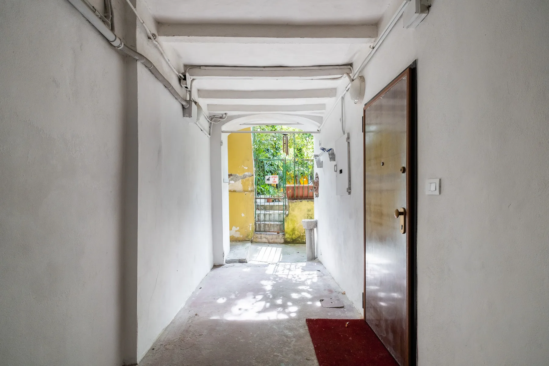 A covered entrance passage leads to a garden gate, with a door along the right wall.