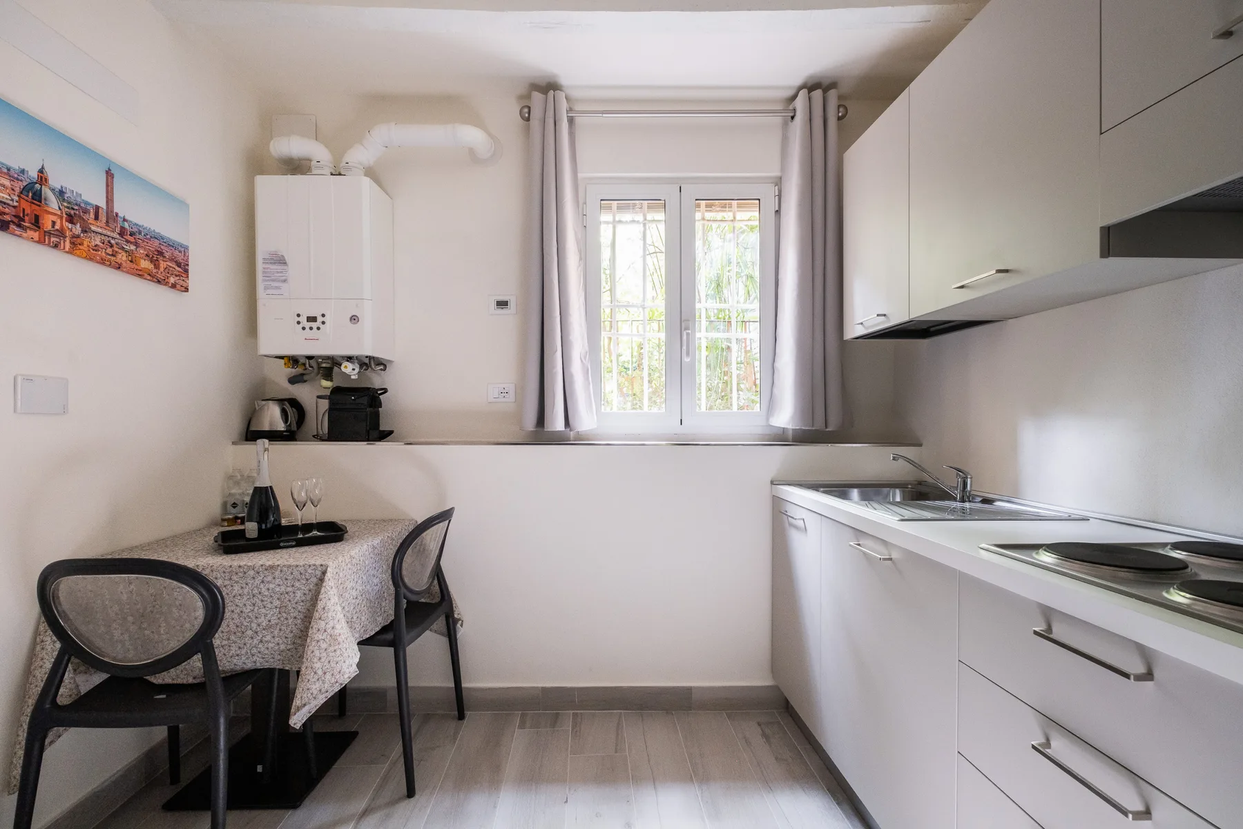 Una cocina compacta y zona de comedor con armarios blancos y una ventana.