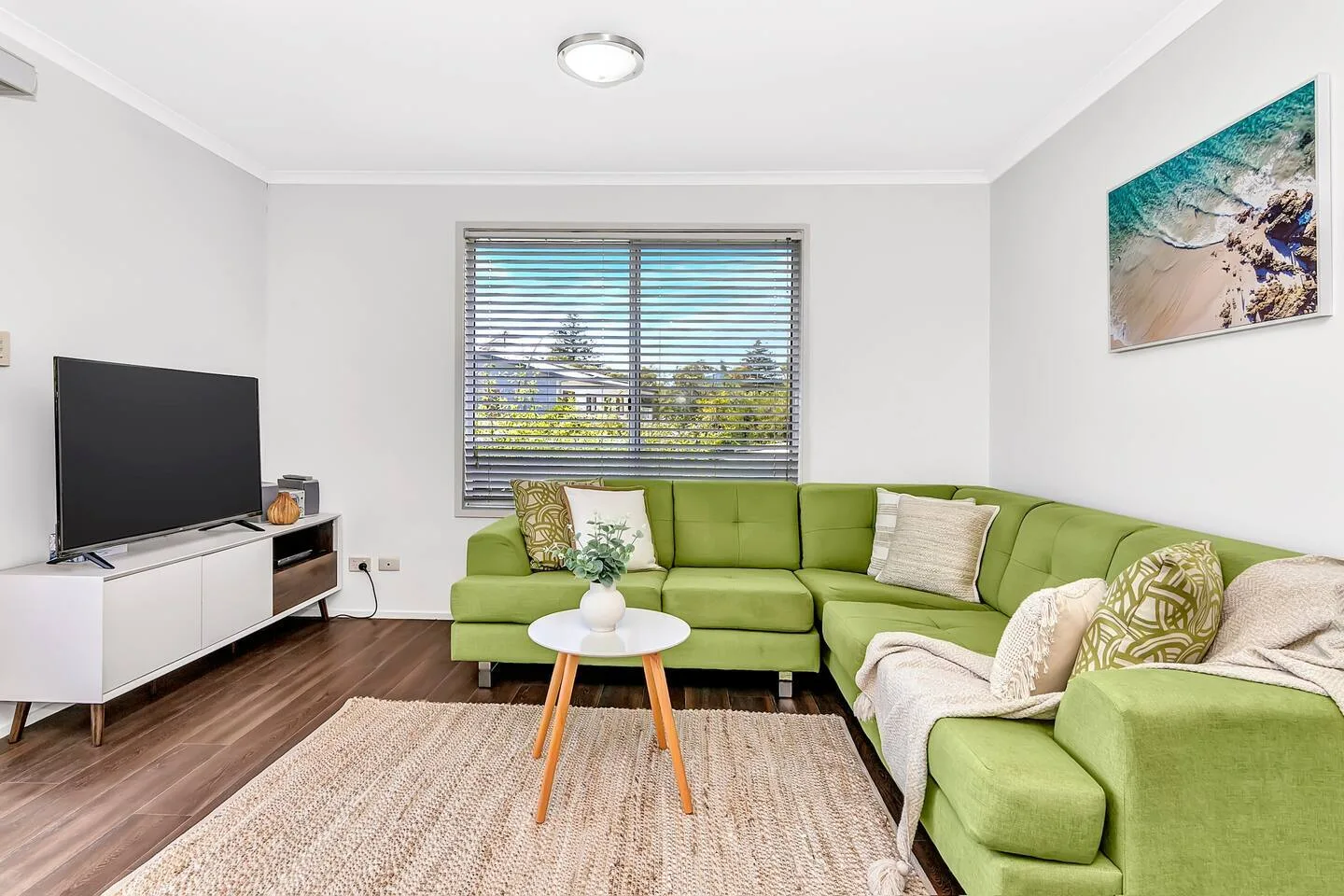 La sala de estar ofrece comodidad con un amplio sofá de color verde lima y un televisor.