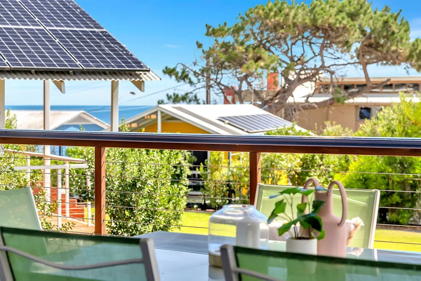 Una zona de comedor al aire libre da a un jardín, con el mar visible al fondo.
