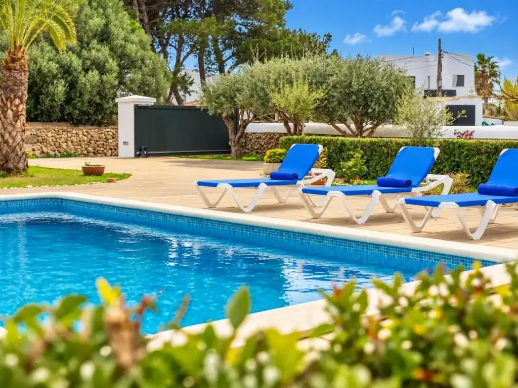 Una piscina al aire libre con tumbonas azules alrededor.