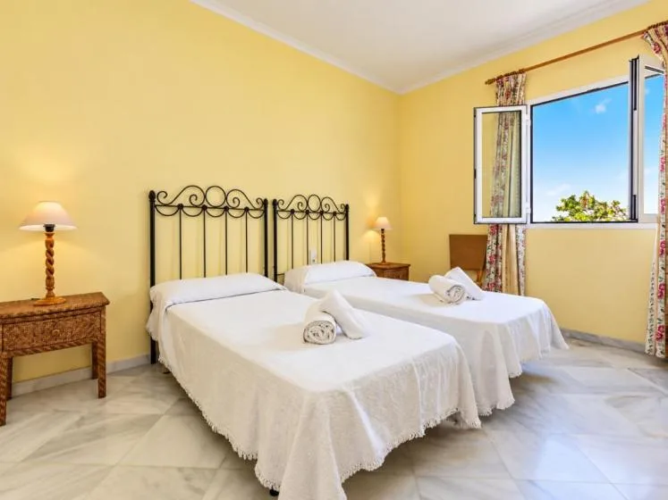 Un dormitorio con dos camas, ropa de cama blanca y una ventana.
