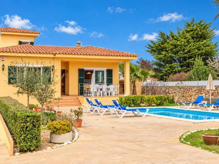 Un patio soleado con piscina, asientos al aire libre y tumbonas.