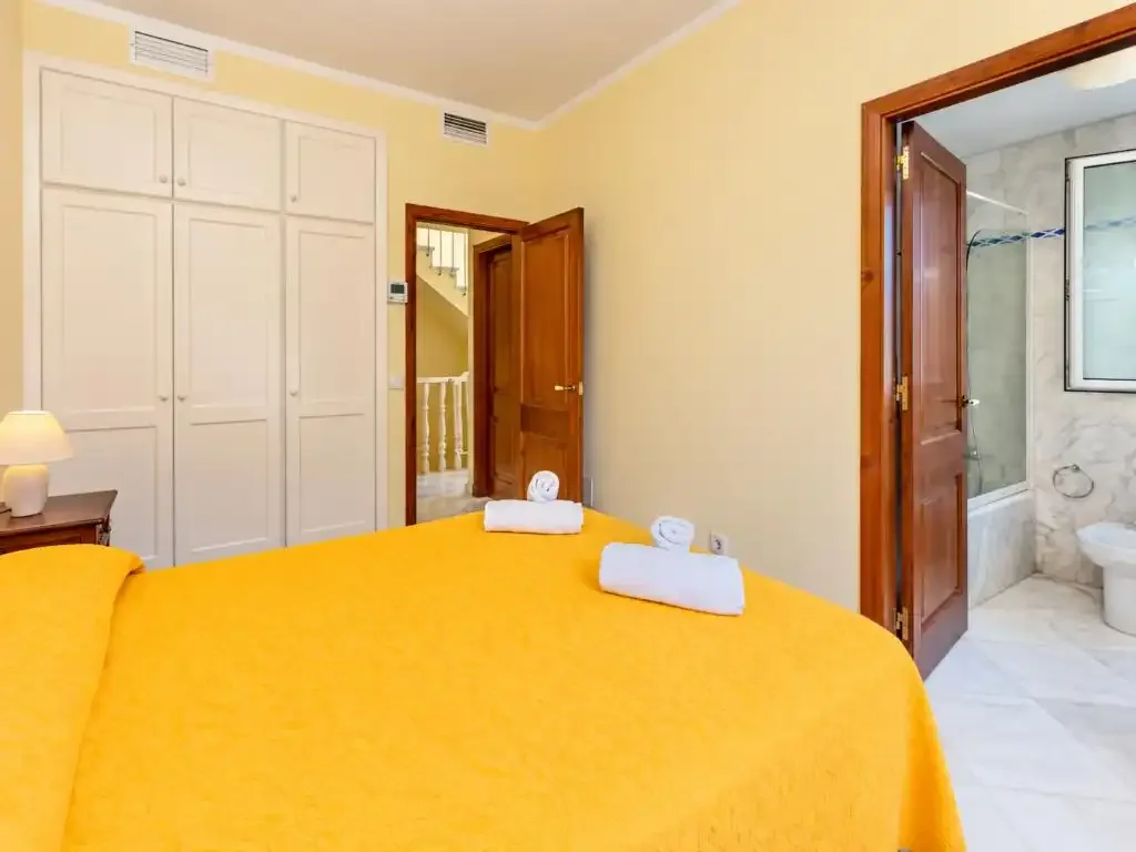 Dormitorio con una cama grande cubierta con una colcha amarilla brillante.