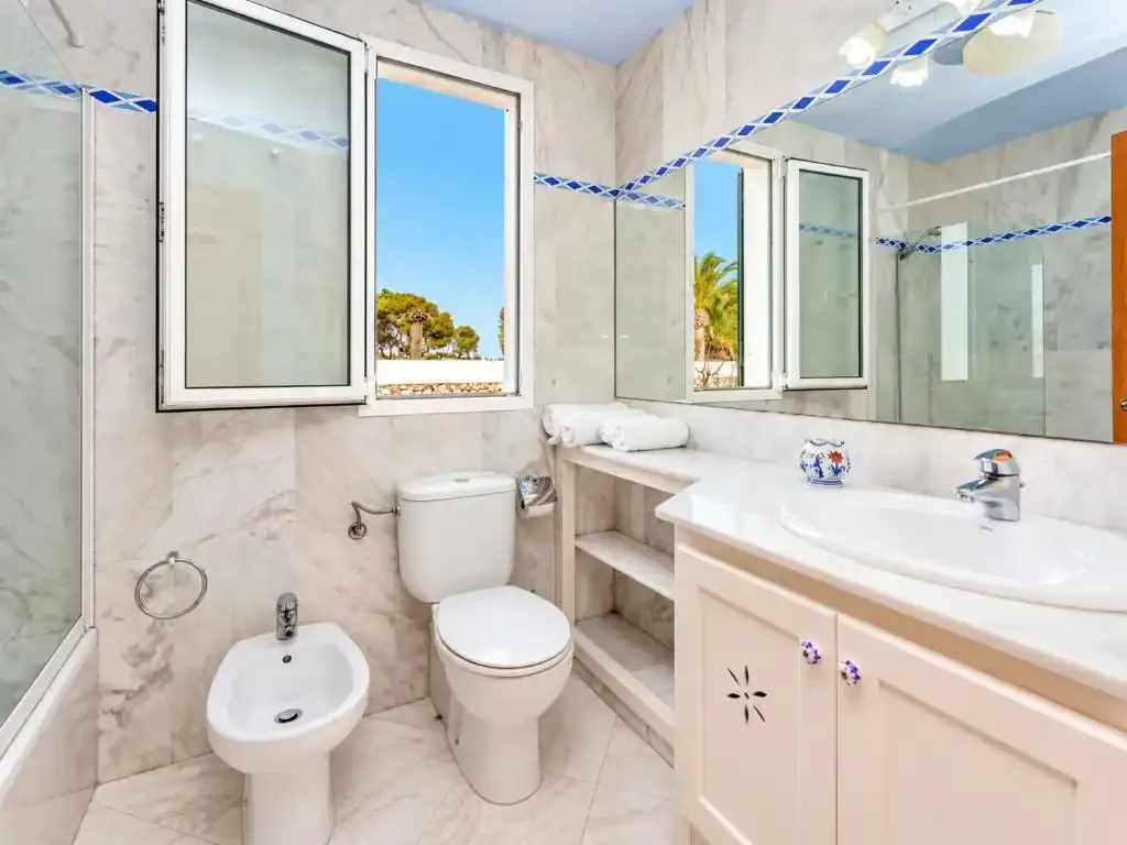Un baño luminoso con lavabo, inodoro y un mueble de baño alargado.