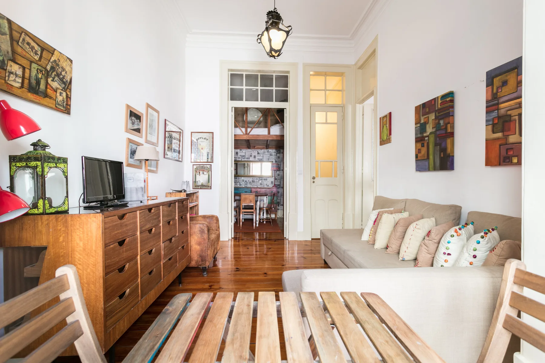 A bright living room with seating, a television, and a wooden table.