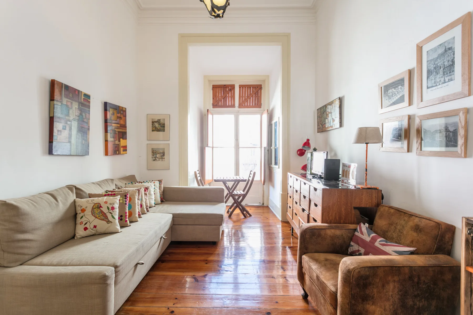 A bright living room with seating, framed artwork, and a wooden floor.