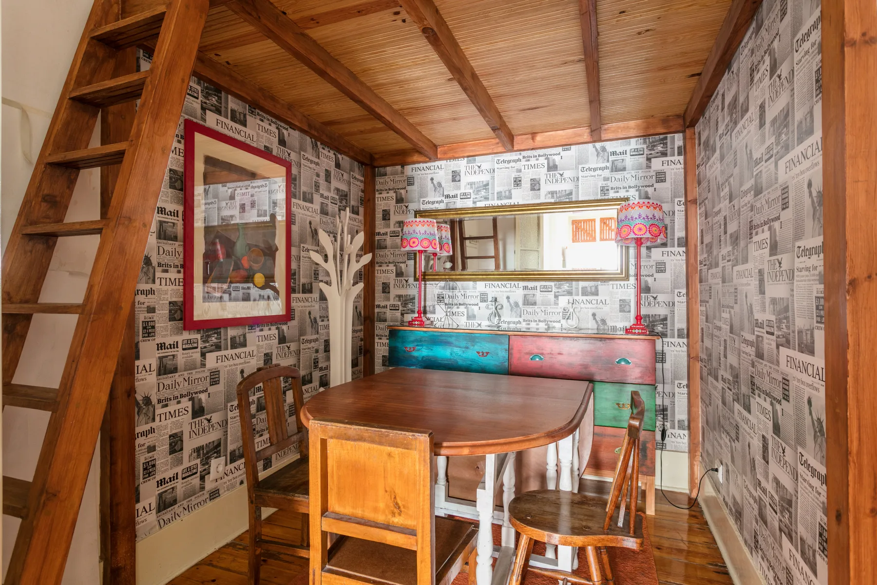 A dining area with a wooden table, seating, and newspaper-print walls.