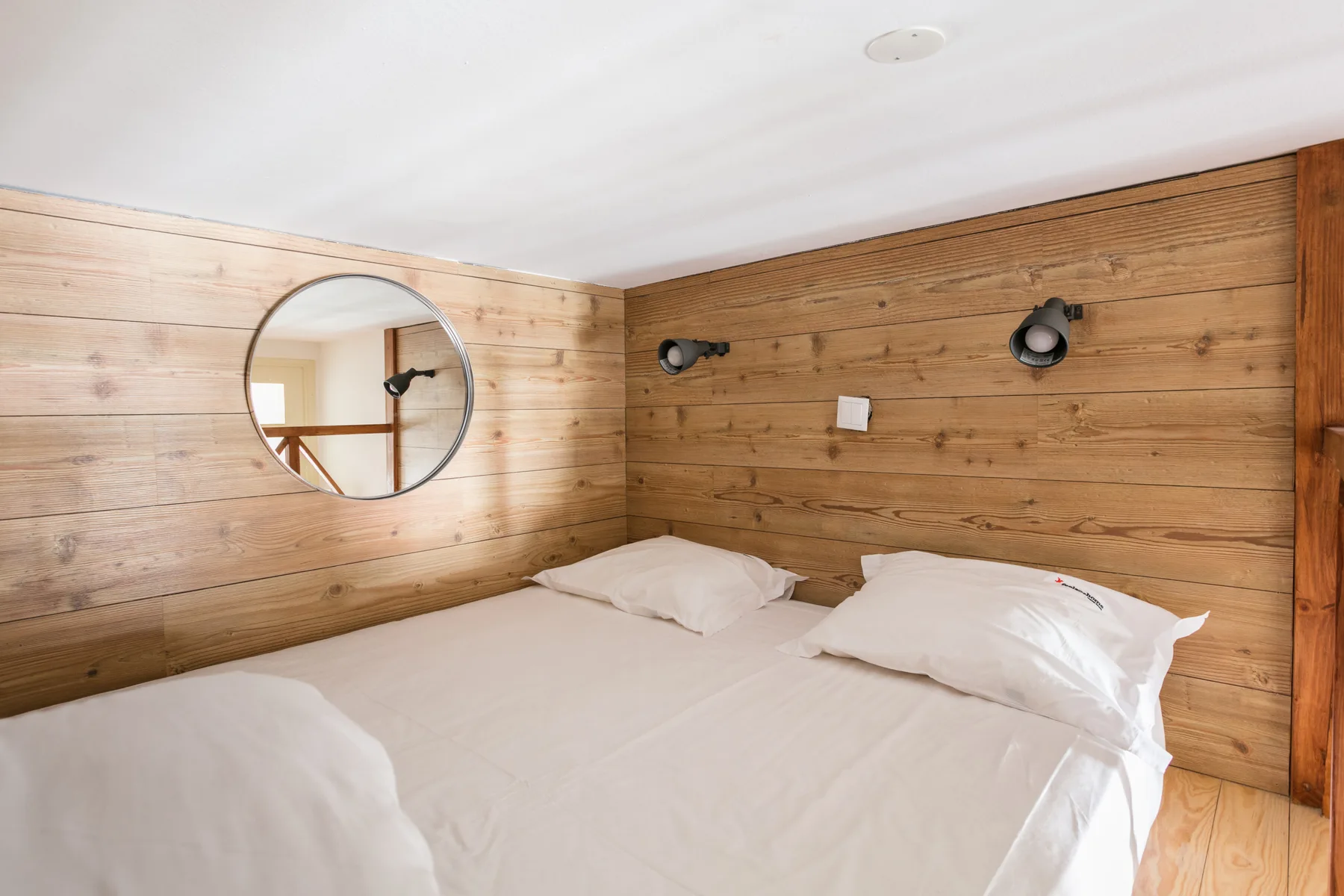 A bedroom with a bed against wood-paneled walls.
