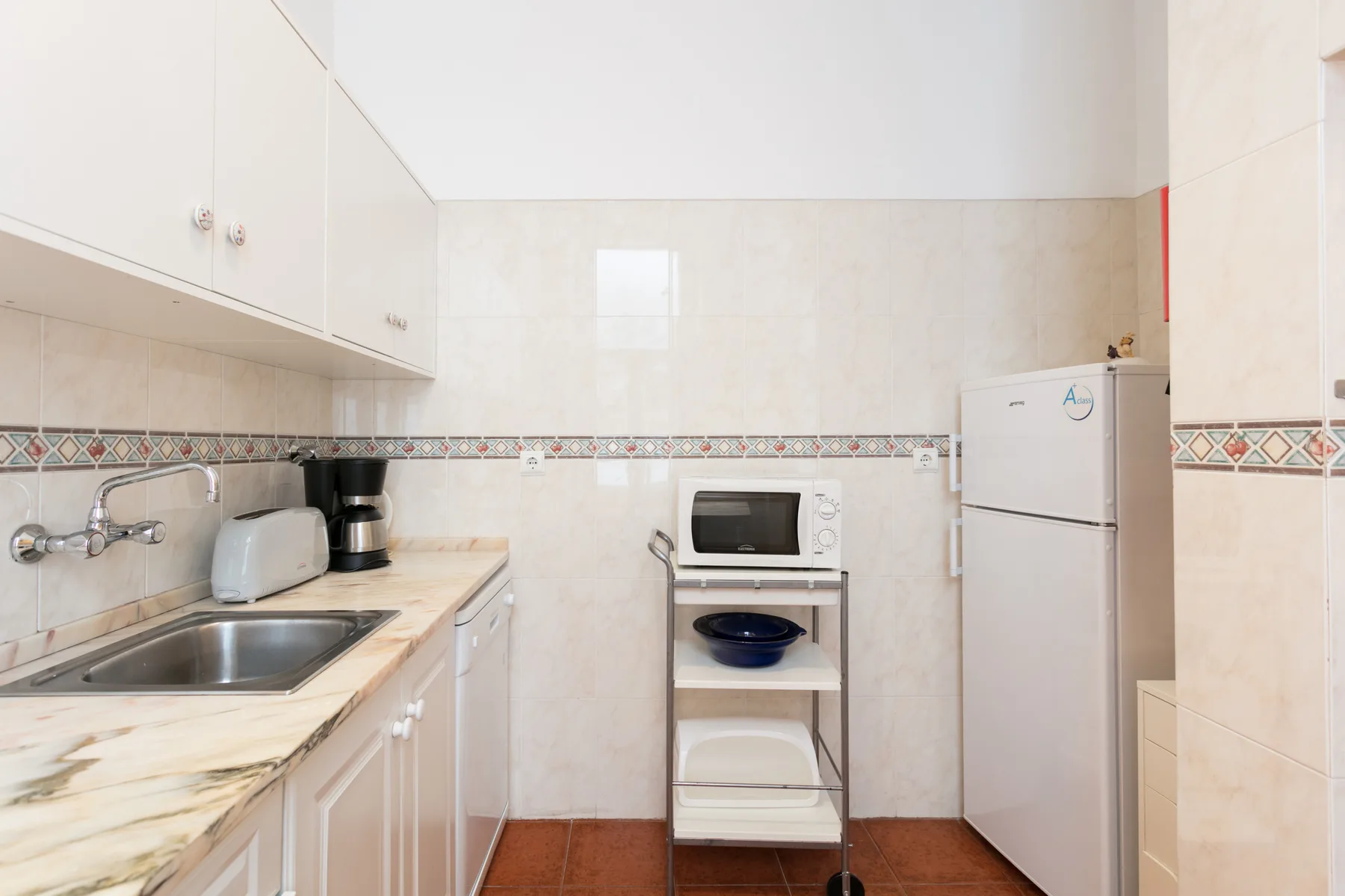 A bright kitchen with a countertop, sink, stove, and refrigerator.