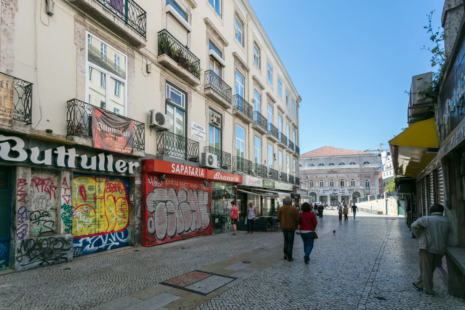 A pedestrian street lined with shops and multistory buildings.