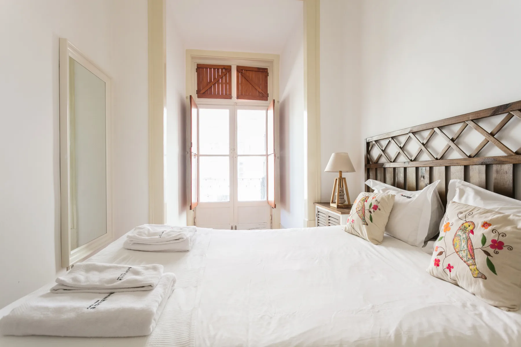 A bright bedroom with a large bed and a window at the far end.