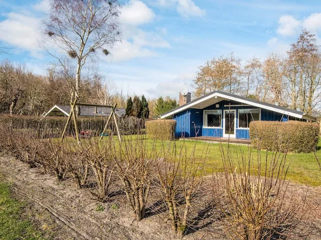 A single-story vacation house stands beside a lawn and trimmed hedges.