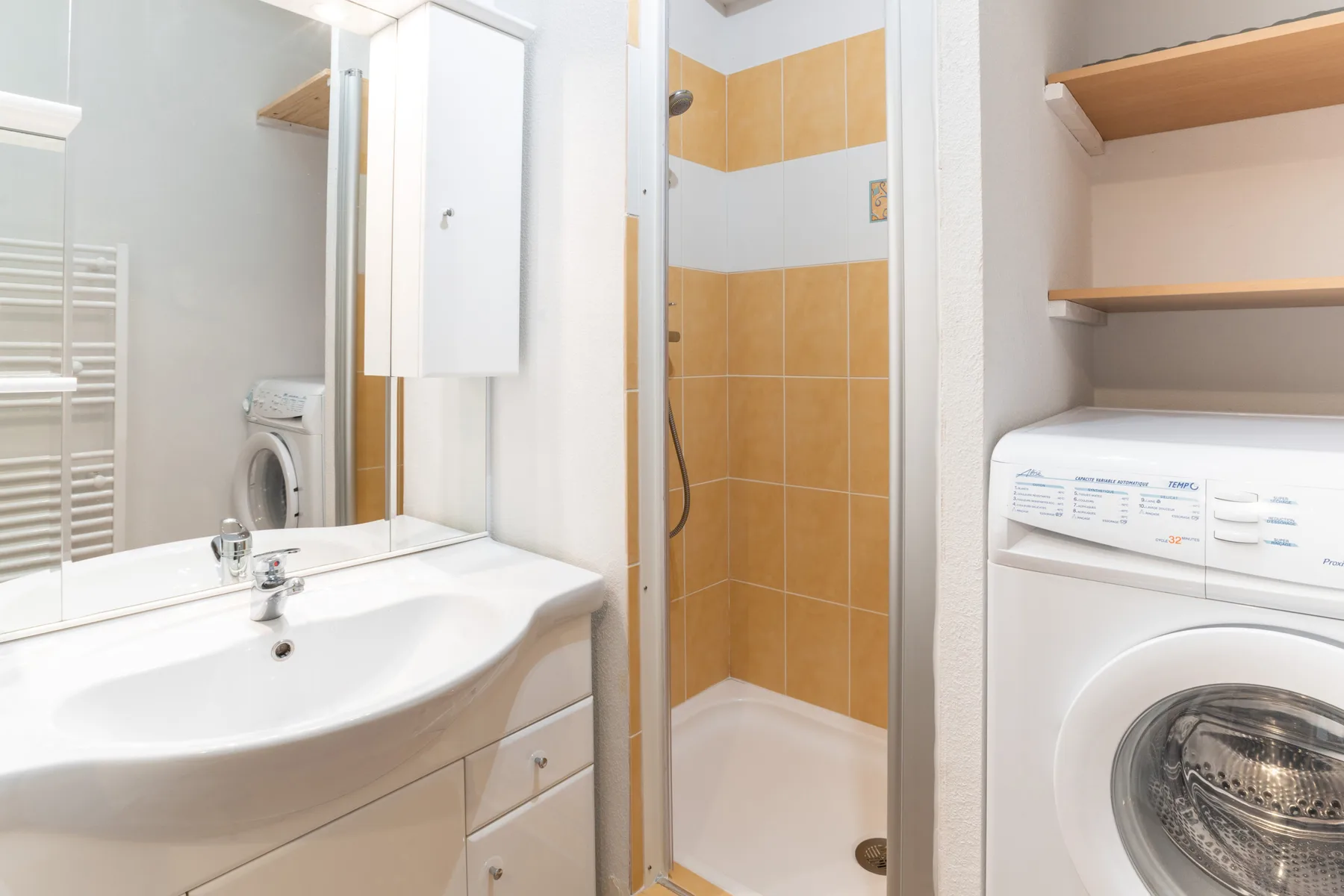 A bathroom vanity, shower, and washing machine are visible in the room.