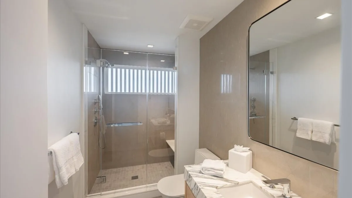 Un baño moderno con una ducha de cristal y un gran espejo de pared.