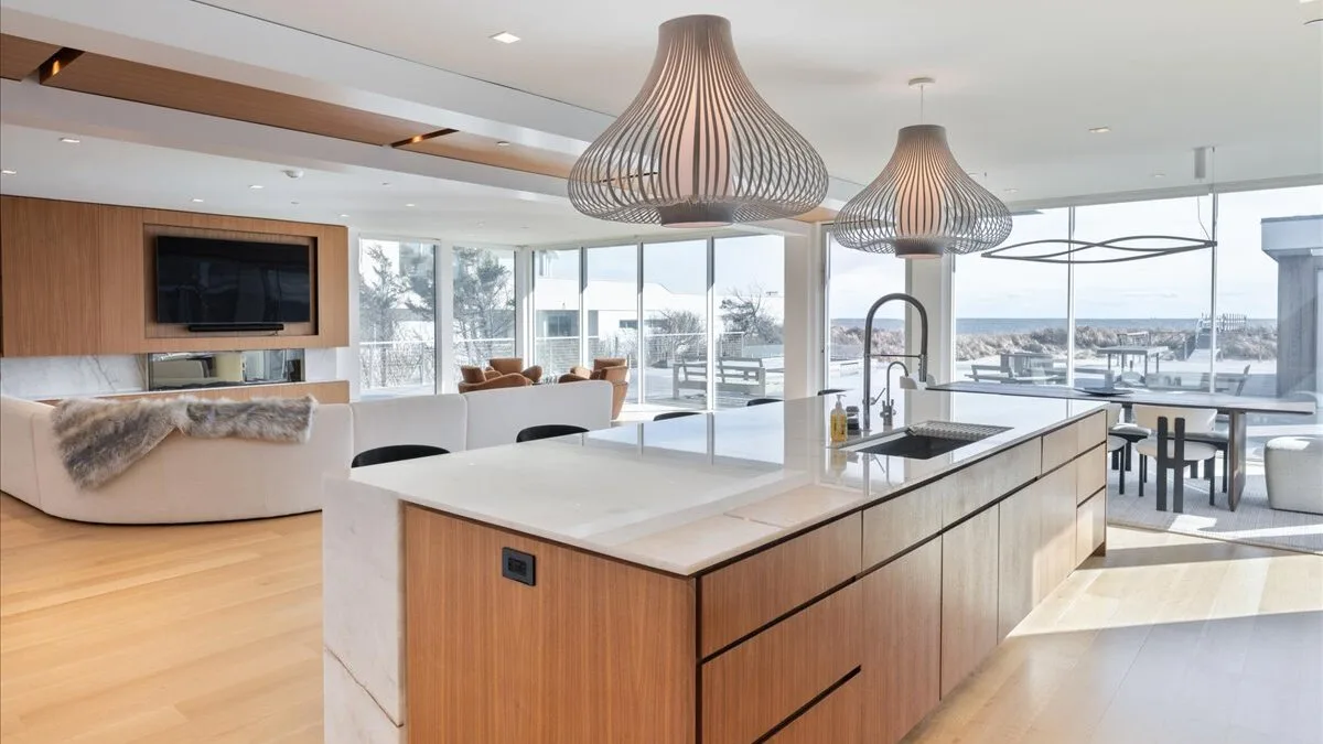 Una cocina moderna con una gran isla y comedor con vistas al agua.