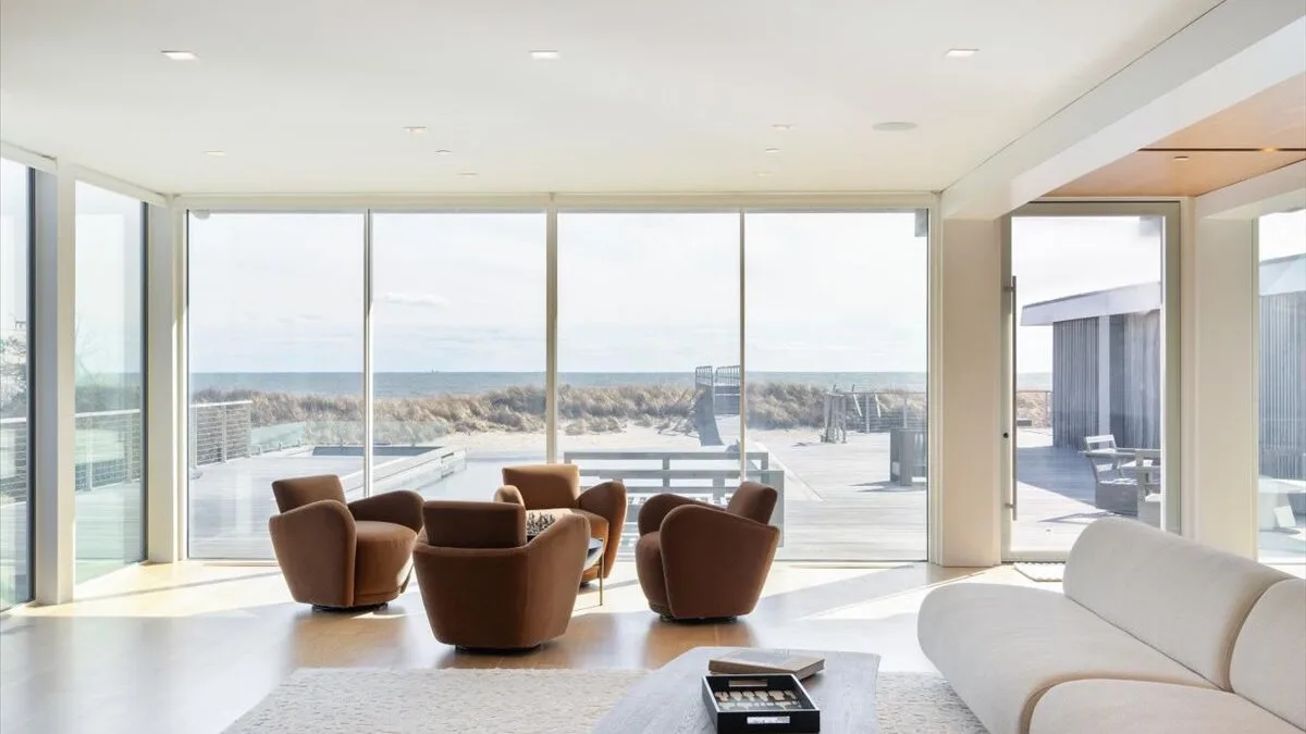 Una sala luminosa con asientos junto a grandes ventanales que dan a una terraza exterior.