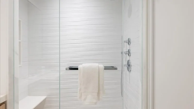 Una zona de ducha con azulejos y una toalla colgada sobre una barra horizontal.