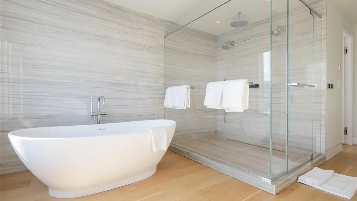 Un baño luminoso con bañera exenta y ducha de cristal.
