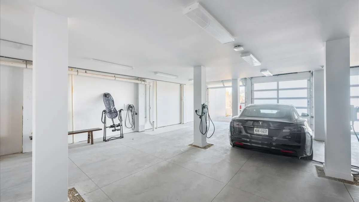 Un estacionamiento interior luminoso con un automóvil oscuro junto a las ventanas.