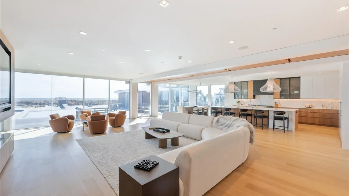 Una luminosa sala de estar y cocina de planta abierta con grandes ventanas y asientos.