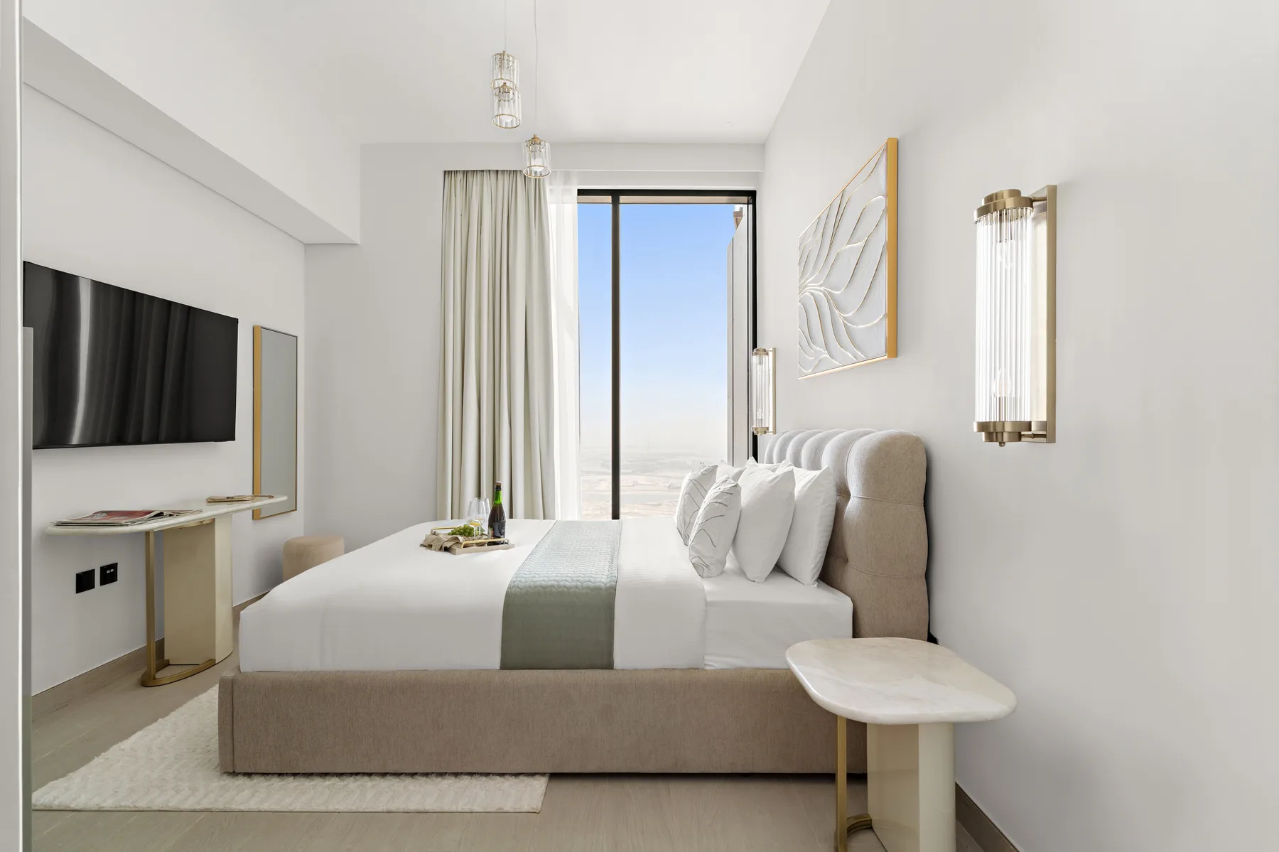 A bright bedroom with a neatly made bed and a large window.