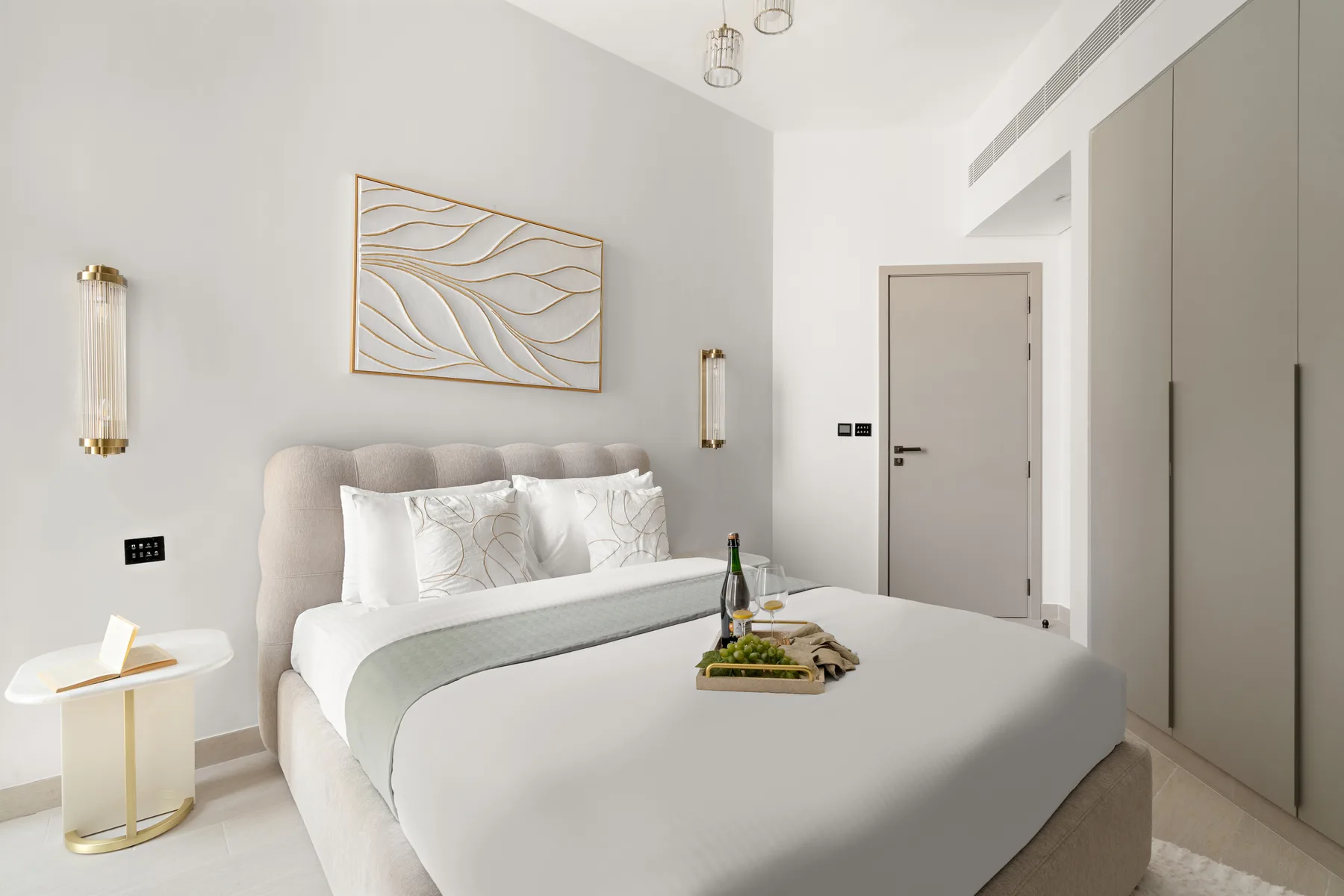A bright bedroom with a neatly made bed and abstract wall art.
