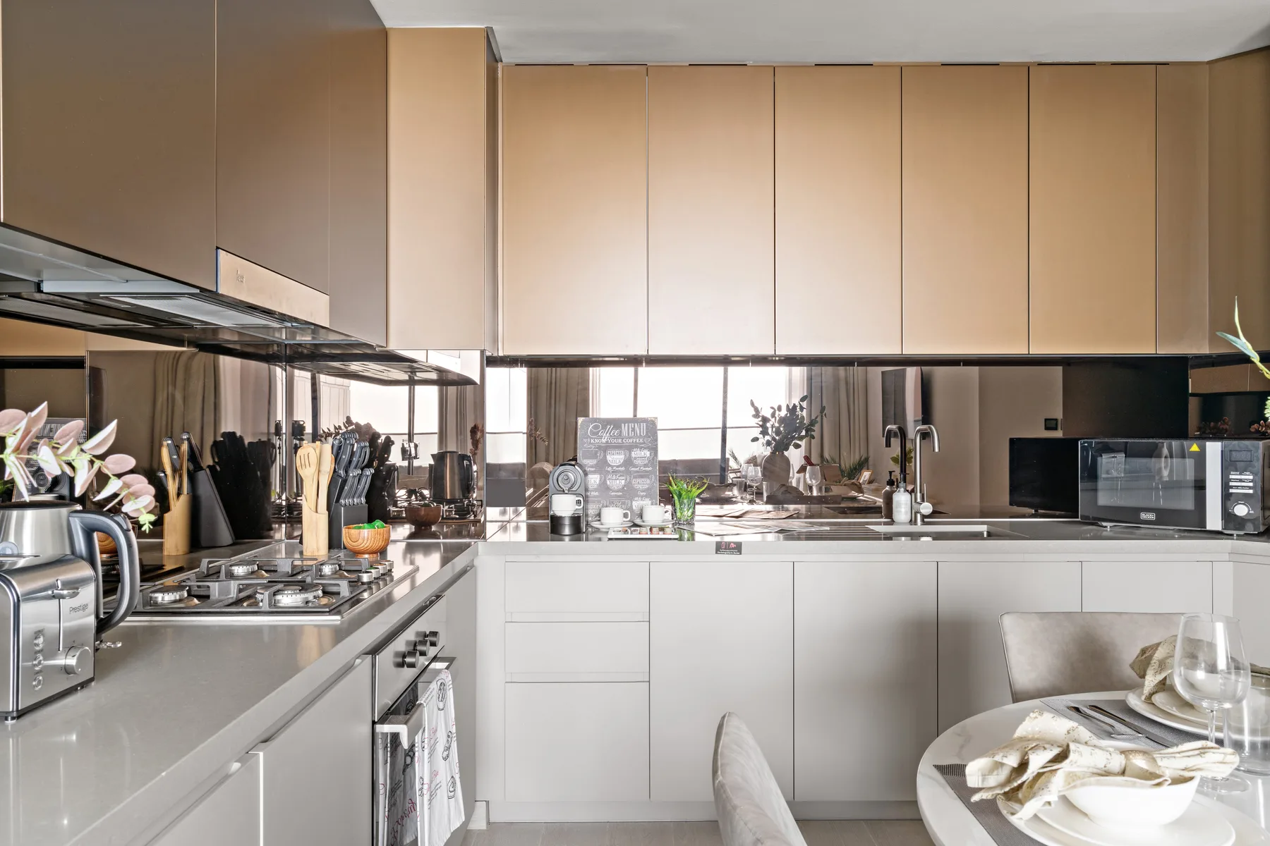 A modern kitchen with light cabinetry, a cooking area, and a dining table.