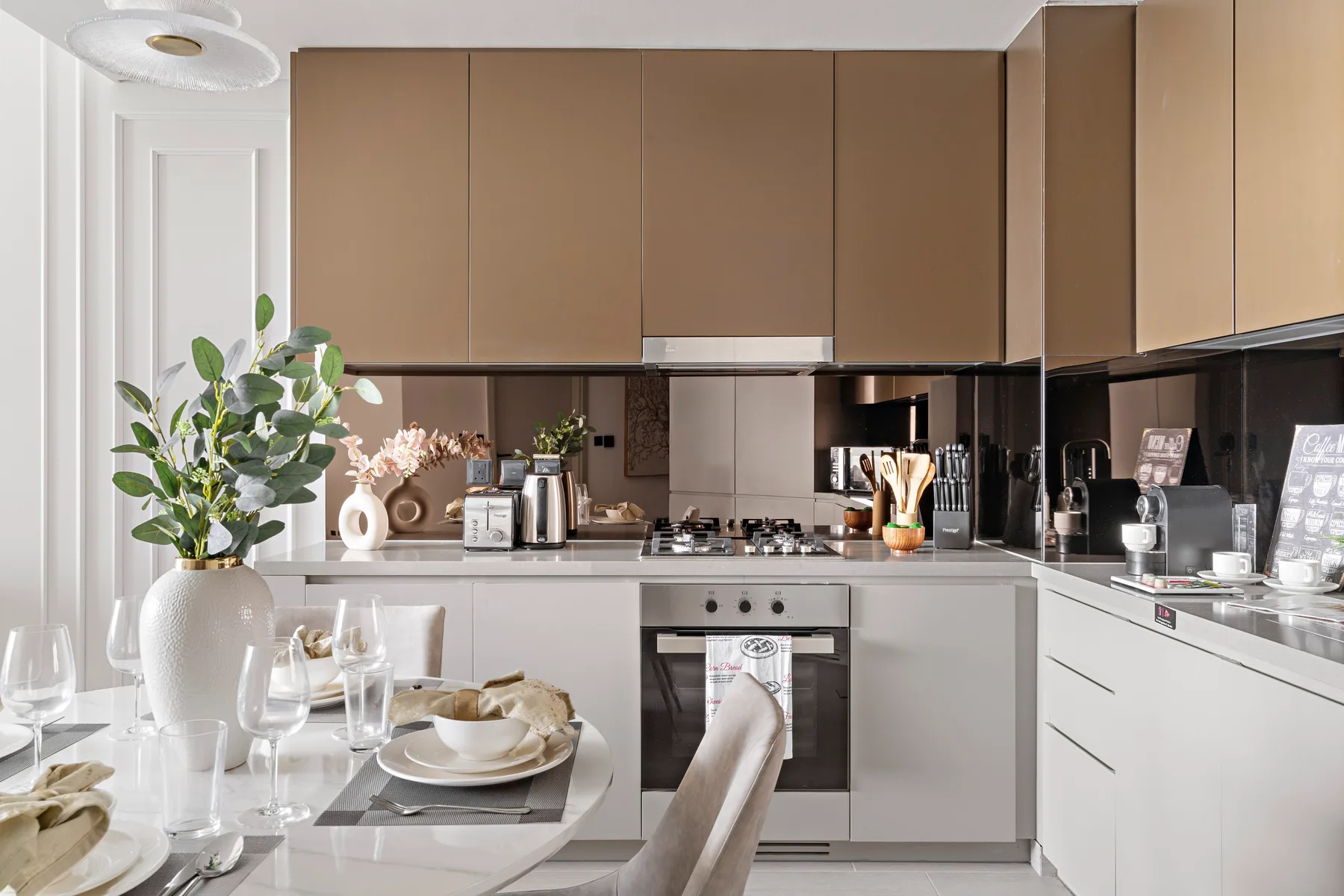 A bright modern kitchen with brown upper cabinets and a dining table.