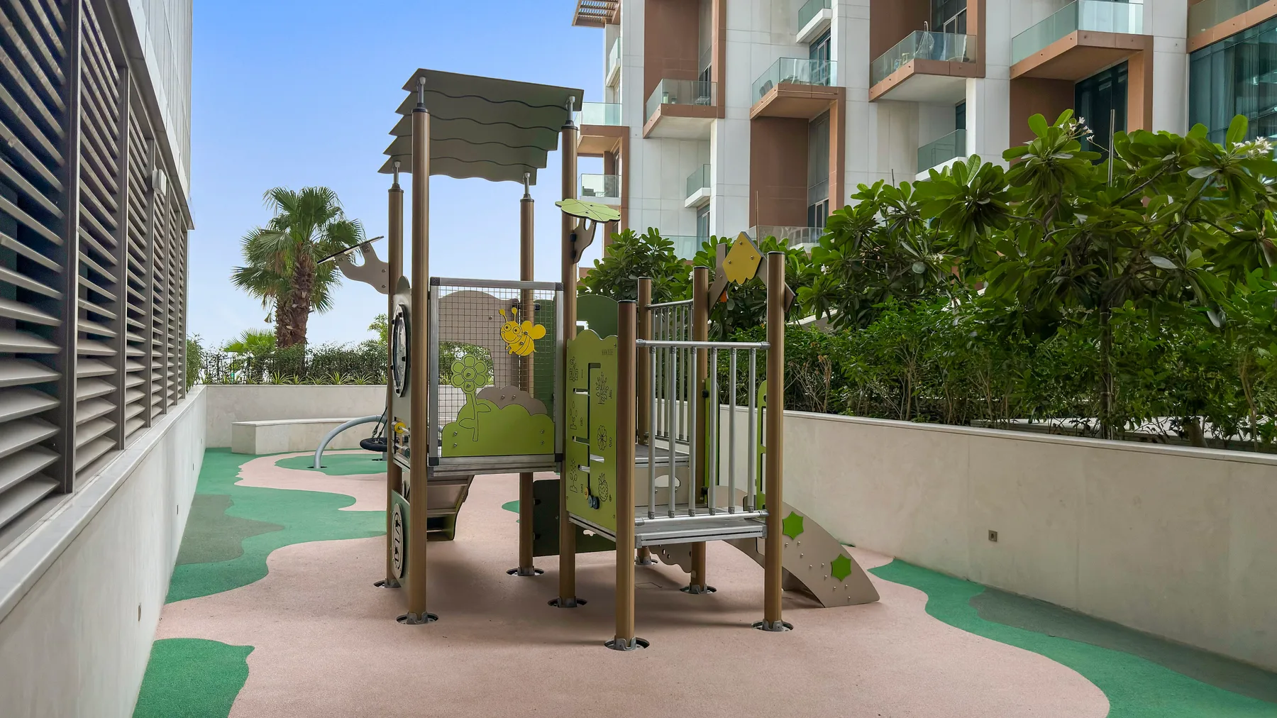 A small outdoor playground with a climbing structure and colorful rubber flooring.