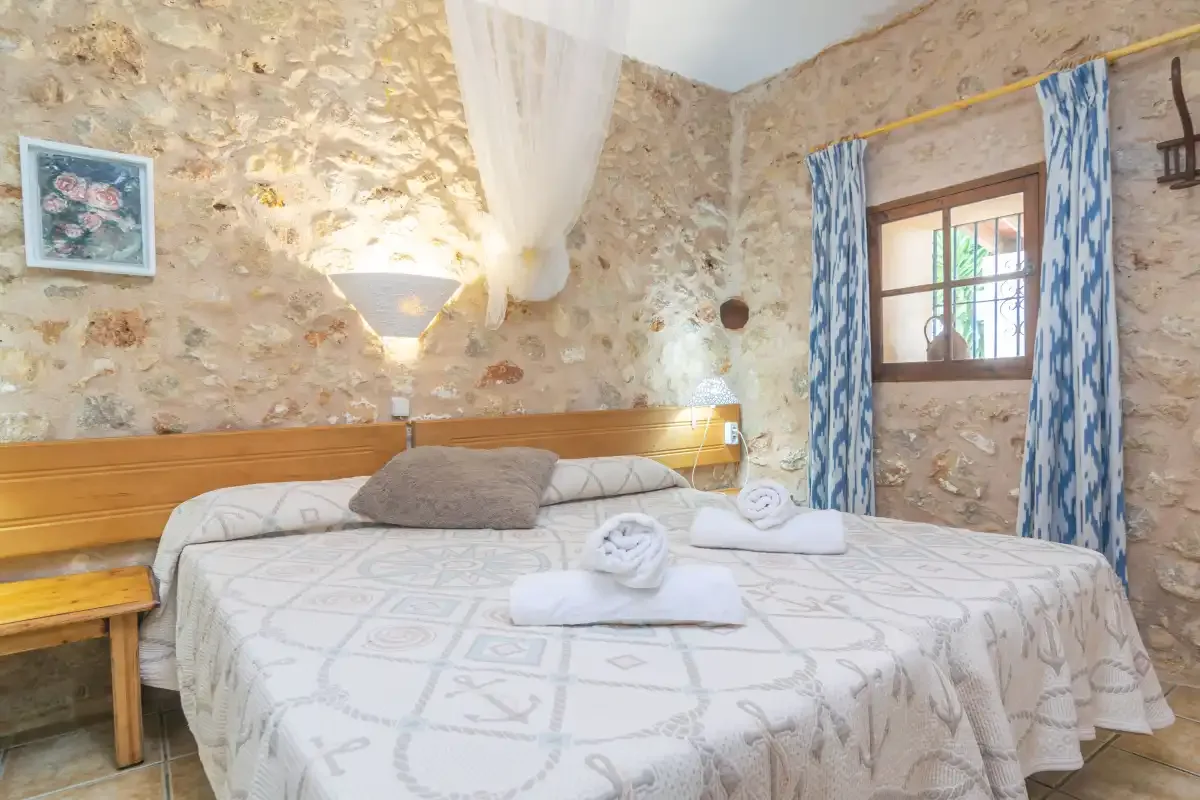 A bedroom with a bed dressed in patterned linens and blue curtains beside the window.