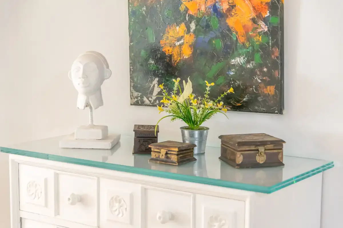 A bright interior features a white display cabinet beneath an abstract painting.