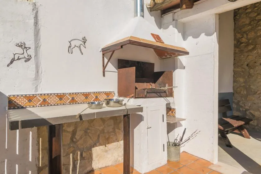 An outdoor cooking area with a built-in grill and tiled work surface.