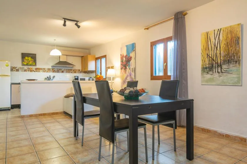 A dining area with a dark table and chairs beside an open kitchen.