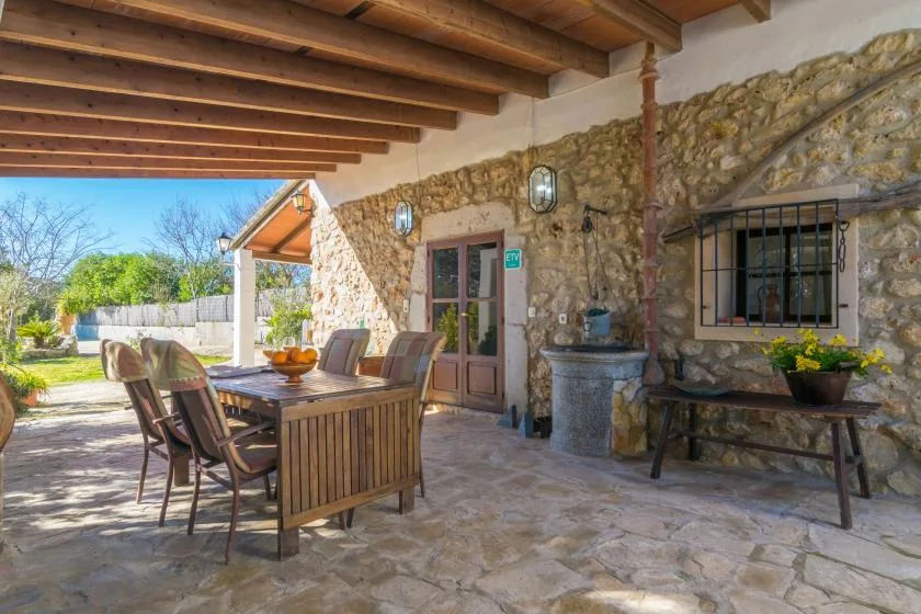 A stone patio dining area sits beneath a timber-beamed roof.