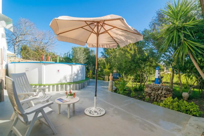 An outdoor patio with a large umbrella, seating, and a garden.