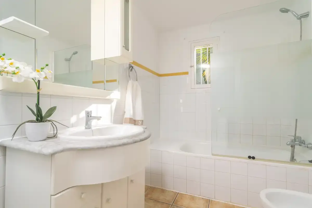 A bright bathroom with a sink, mirror, and bathtub.