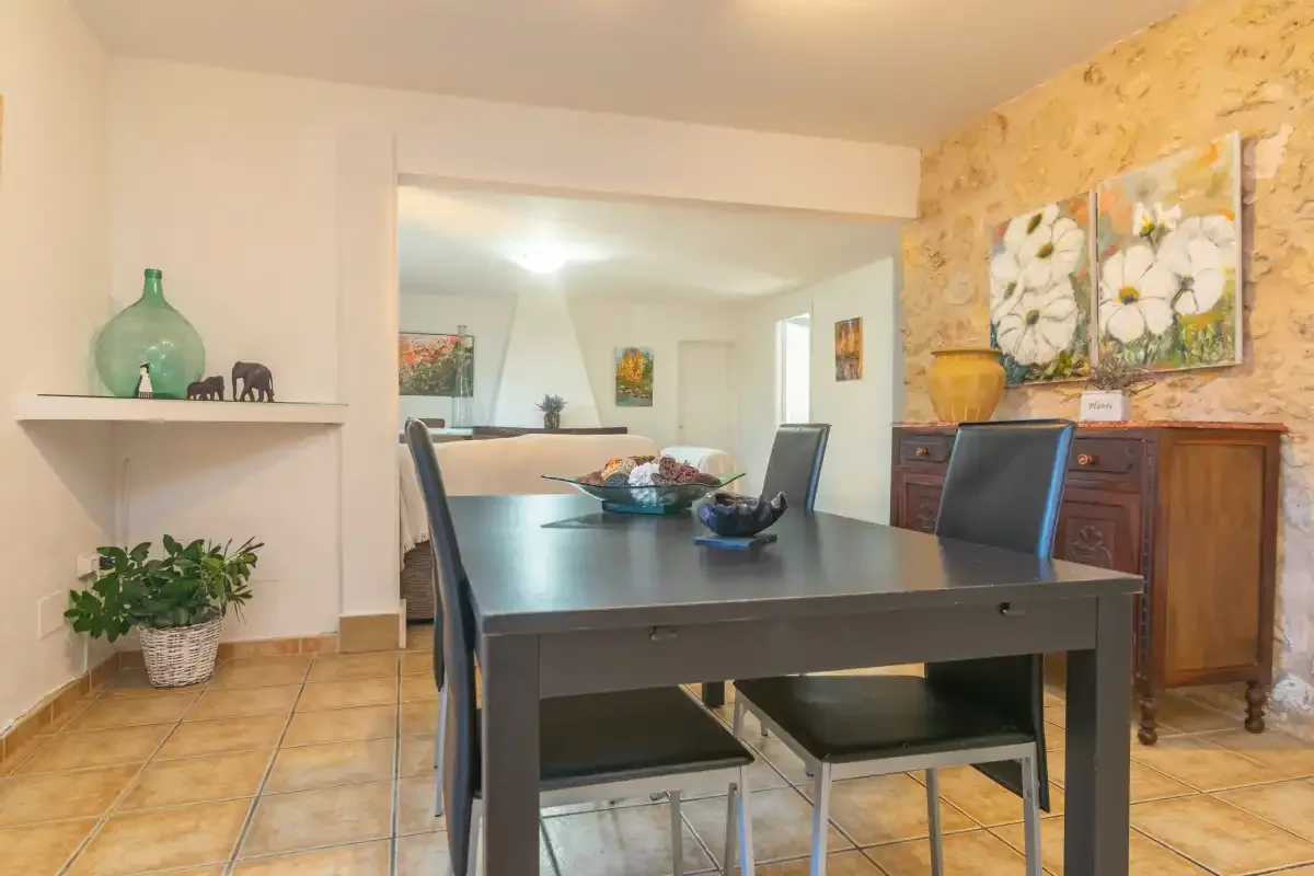 A dining area with a dark table and chairs, beside a wooden sideboard.