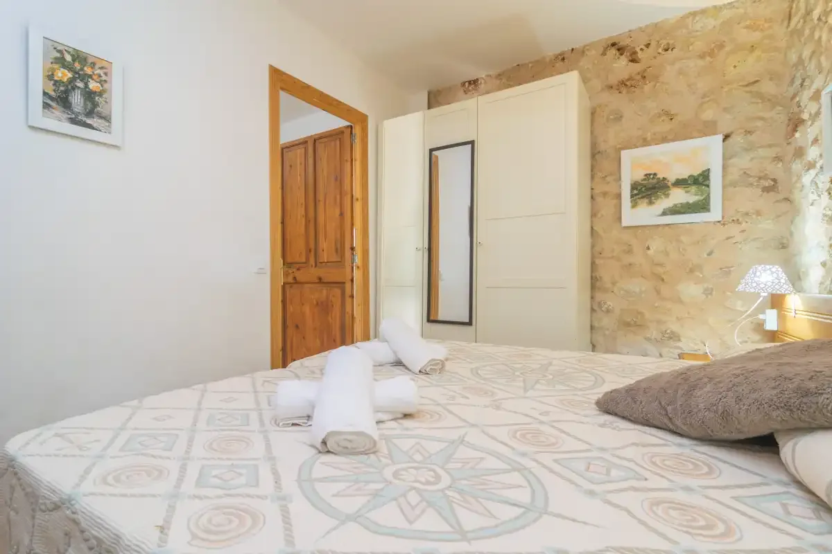 A bedroom with patterned bedding, a wooden door, and stone walls.