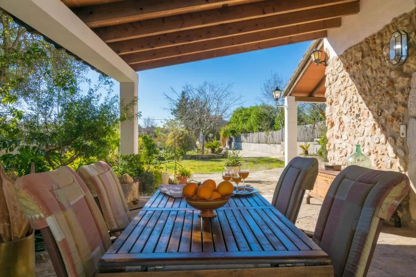 A covered outdoor dining area with a wooden table and garden views.