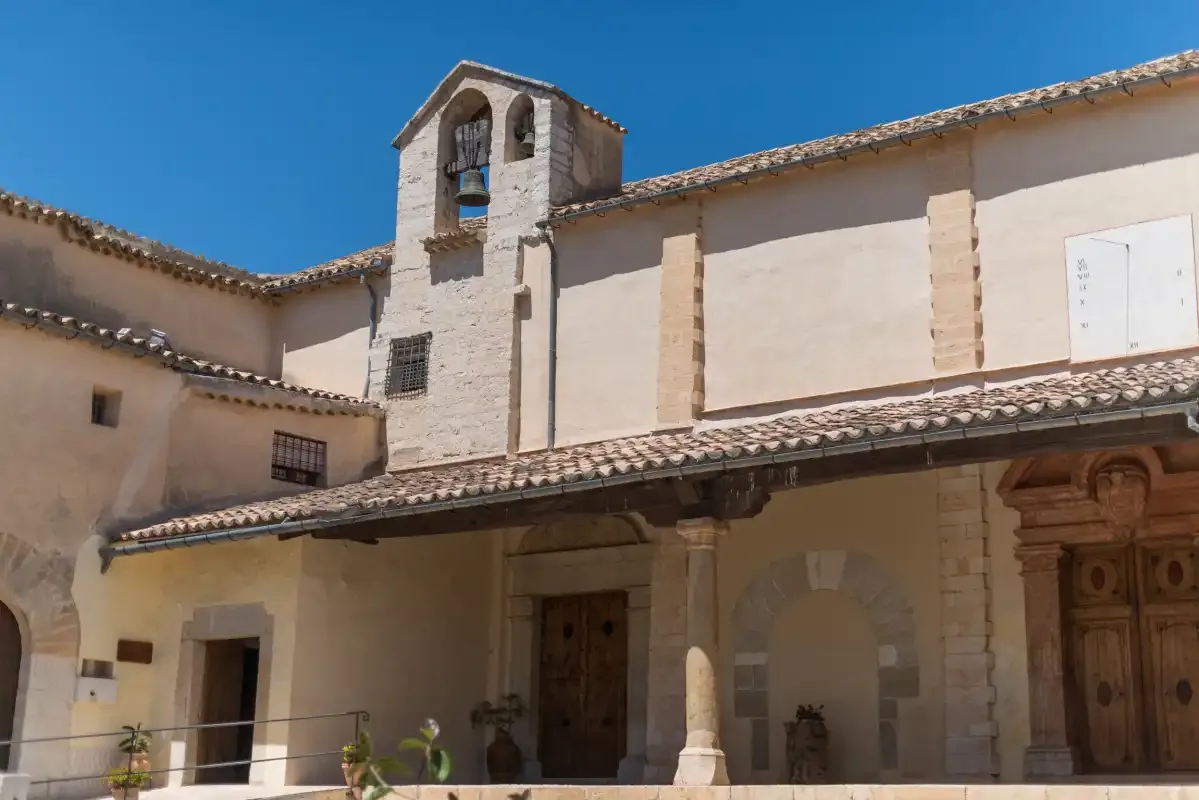 A historic-looking building with a bell tower and a shaded entrance.