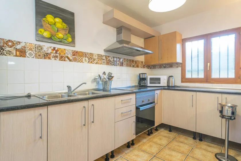 A bright kitchen with light cabinets, a tiled backsplash, and a built-in oven.