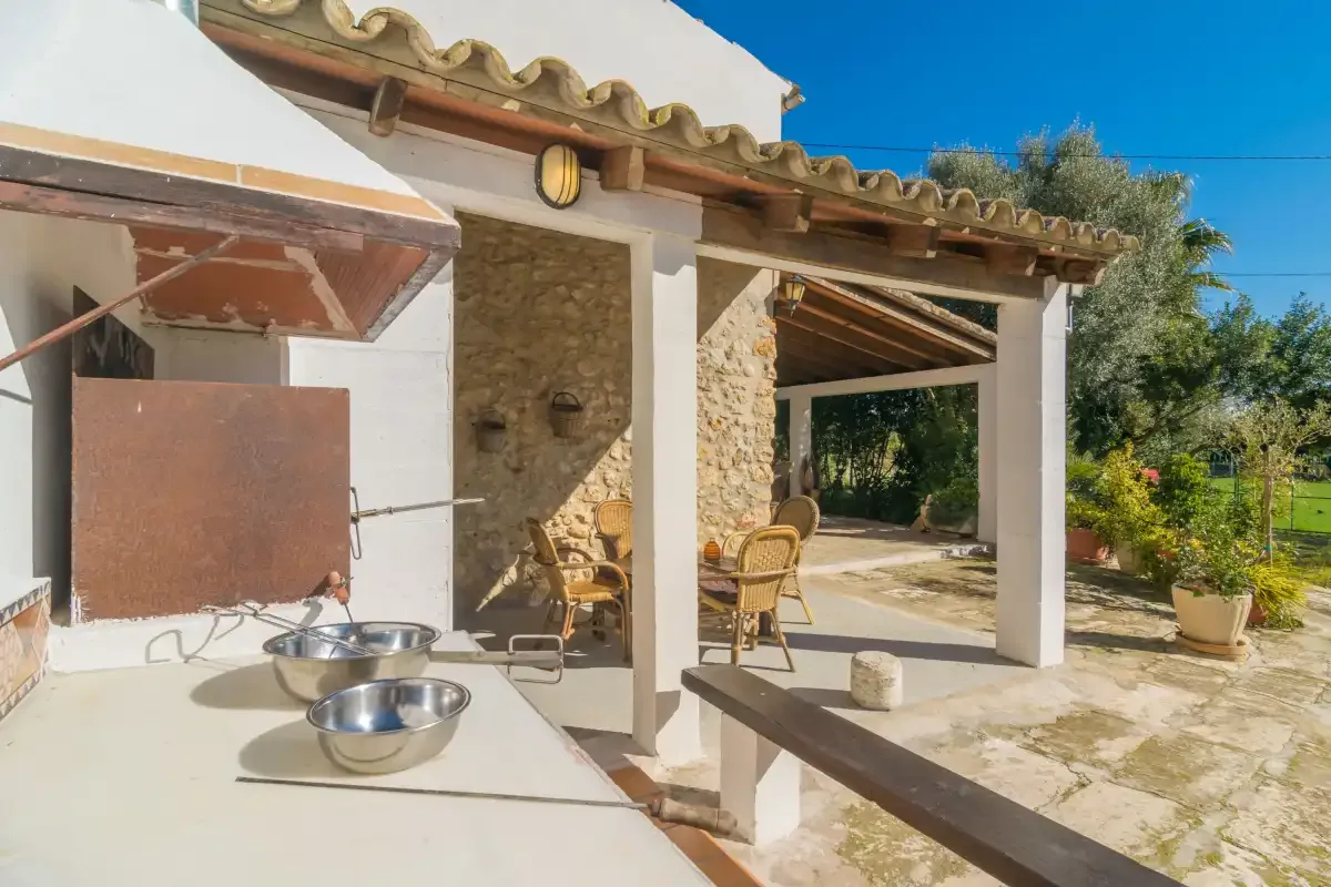 A covered outdoor patio with a barbecue counter and seating.
