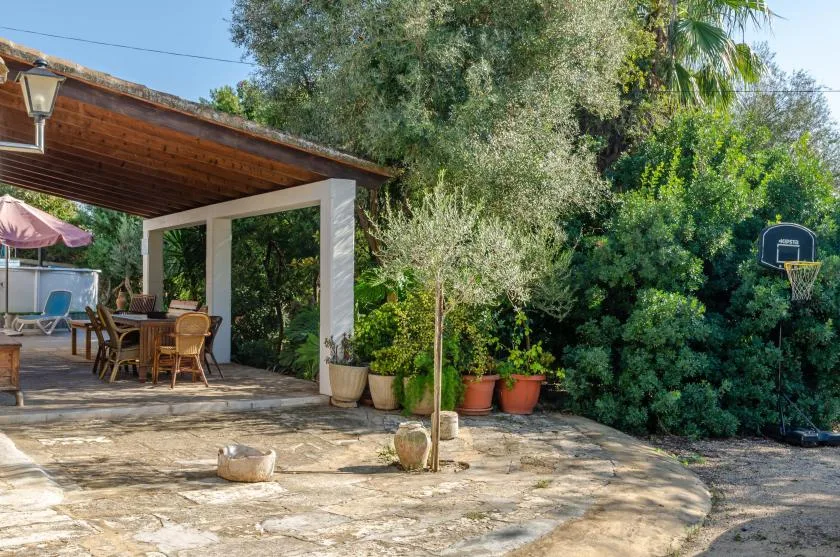 An outdoor patio with a covered dining area and surrounding greenery.
