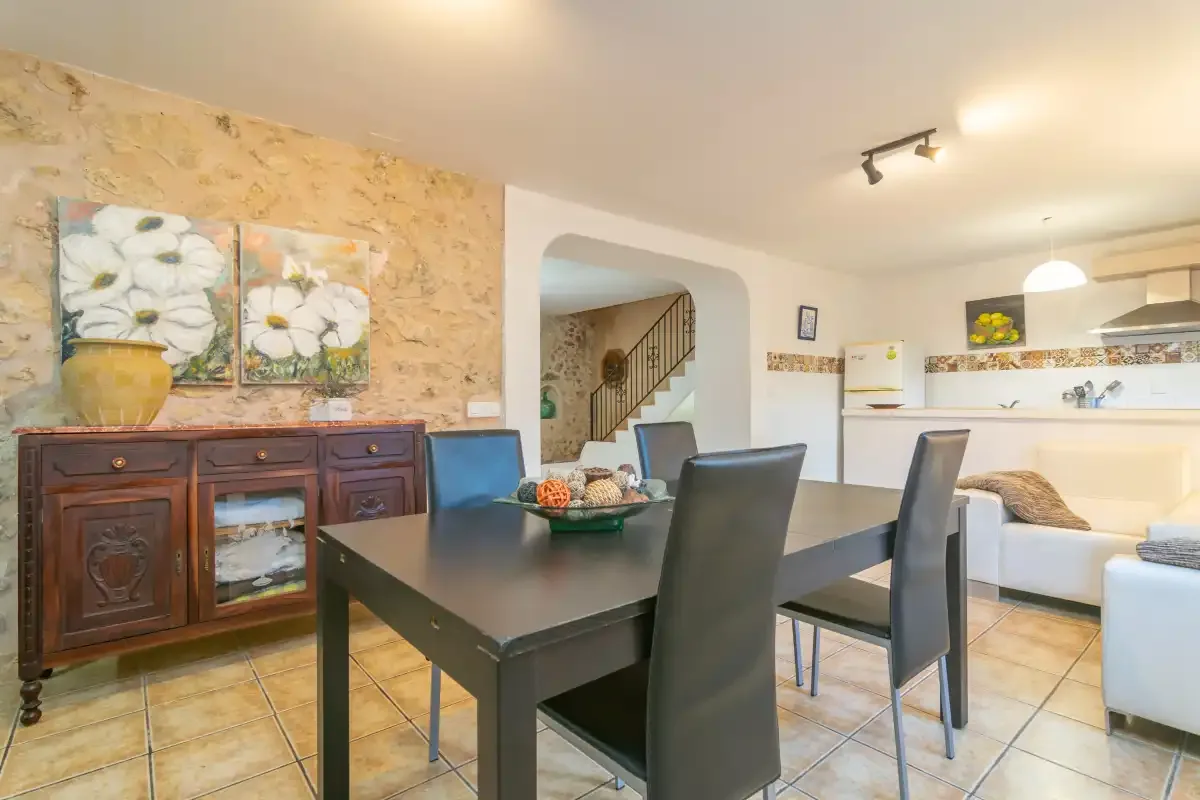 A dining area with dark seating beside an open kitchen and living space.