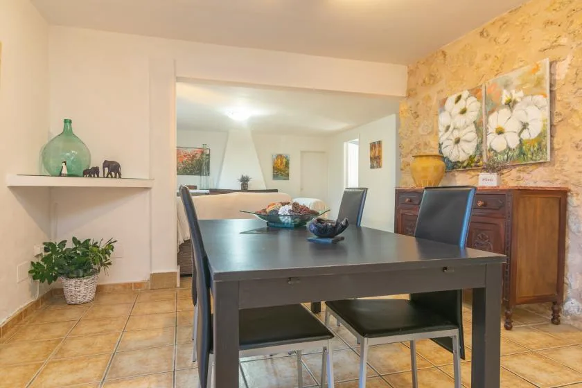 A dining area with a dark table, chairs, and floral wall art.